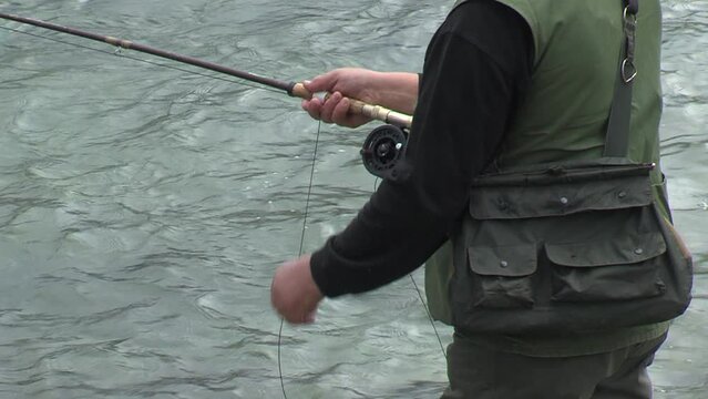 fisherman fishing in river, spinning reel, pulling algae on hook out of water, tilt