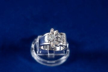 ring made of white gold with natural diamonds, a frame like a flower, on a blue background