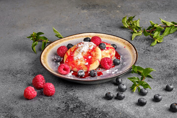 Fragrant baked cottage cheese cakes with fresh berries and jam on the breakfast table