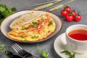 Delicious baked omelet with vegetables and a cup of tea on the breakfast table close-up