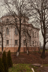 Fototapeta premium An old building in a park behind trees .