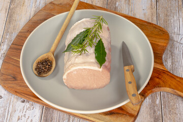 raw roast pork in a plate on a wooden background