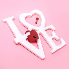 Valentine's Day. Gifts in the form of hearts on a pink background with the inscription love. Copy space for text. The concept of romance and love. Lock and key from the heart.