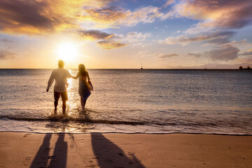 A happy holiday couple enjoys a tropical beach during golden sunset time and runs in the sea