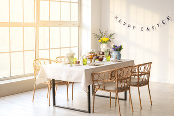 Interior of light room with table set for Easter celebration near big window