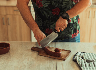 Man cutting sausage in the kitchen 