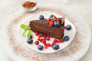 Plate with delicious piece of chocolate cake and berries on light background