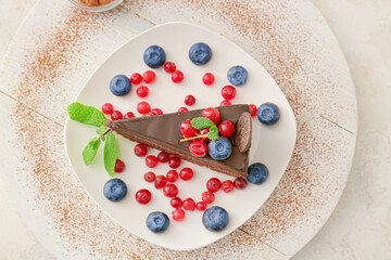 Plate with delicious piece of chocolate cake and berries on light background
