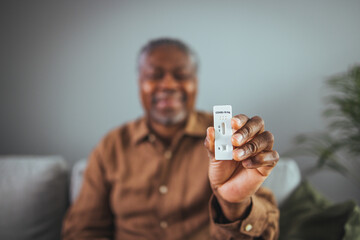 Old senior African American male hand nasal swab testing rapid tests by himself for detection of...