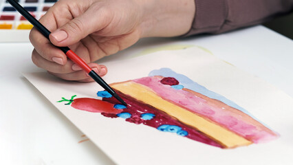 a hand with a brush draws a cake with watercolors, graphic arts