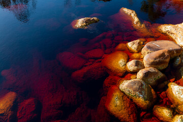 Fototapeta na wymiar The 'Rio Tinto' river, in Huelva, Spain, whose waters dye the rocks of its bed in bright colors due to the minerals from the mines