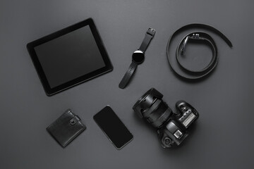 Set of modern gadgets, belt and wallet on dark background