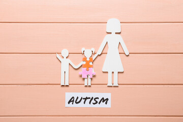 Figure of family and puzzle pieces with word AUTISM on color wooden background - Powered by Adobe