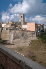 Fototapeta na wymiar Miglionico, Matera. Panorama del borgo sullo sperone roccioso con il campanile della Parrocchia S. Maria Maggiore 