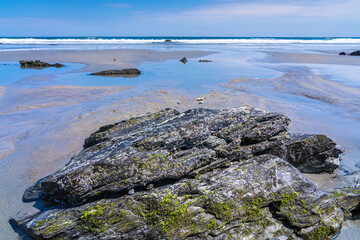 Huge shell-covered smooth rocks in the sand at low tide against the backdrop of the Atlantic Ocean on Hampton Beach. In 2011 it was named one of the four 
