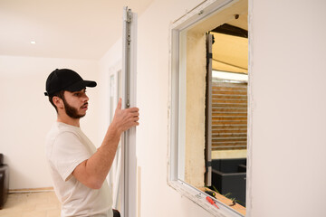 Fototapeta na wymiar handsome young professional man installing and replacing a new home windows in client house for improvement energy saving efficiency isolation
