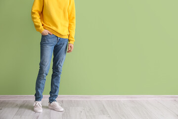 Fashionable young man in stylish jeans near color wall