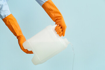 Man pouring out liquid from plastic canister on color background