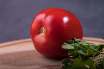Juicy red tomato with a sprig of parsley close-up on the table. - 487959519