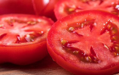 A red, ripe tomato is cut into round slices in close-up. - 487959564