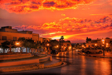 Inusual escena nocturna de una avenida  en La Marsa (Túnez)  sin vehículos ni personas en un atardecer con un cielo rojo que tiñe toda la avenida con su color predominante.