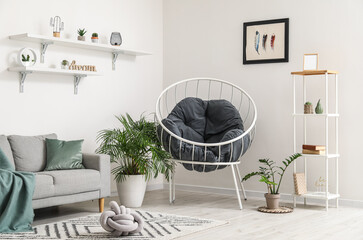 Interior of light living room with grey sofa, armchair and houseplants