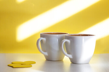 Two cups of black coffee on sunny yellow background. Happy lovely morning concept.