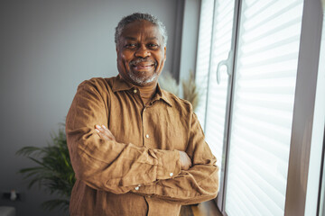 African American Senior Man at home Portrait. Smiling senior man looking at camera. Portrait of black confident man at home. Portrait of a senior man standing against a grey background
