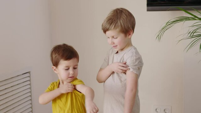 Two little kids after vaccination to protect COVID-19 disease with adhesive plaster