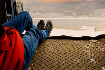 Traveler rests in the trunk of his car after a day on the mountain route and watching the sunset.