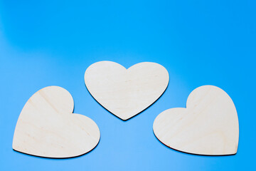 three wooden hearts on a blue background close up