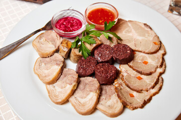 Krovyanka, homemade sausage, boiled pork with horseradish and adjika on a white plate