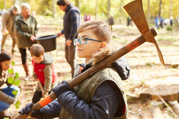 Junge trägt eine Dechsel Axt und hilft beim Bäume pflanzen - obrazy, fototapety, plakaty