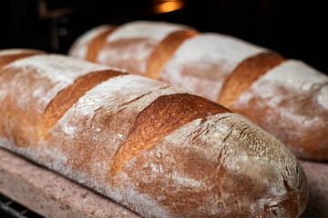 Homemade wheat loaves are baked in the oven on a baking stone. Close-up, selective focus