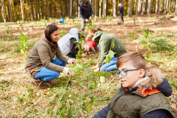 Kind und freiwillige Aktivisten beim Baum pflanzen im Wald