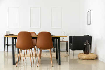 Interior of light dining room with table and black armchairs