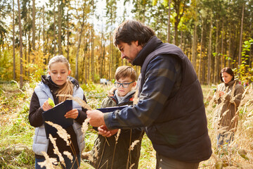 Förster und Kinder beim Baumkunde Unterricht im Wald