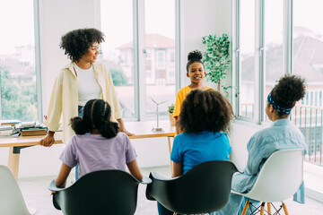 Young adolescent African American boy talking in front of classroom while female teacher and...