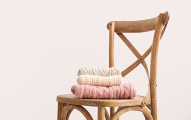 Chair with knitted sweaters on light background