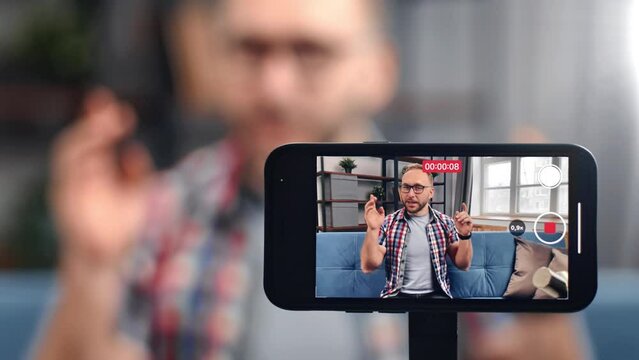 Friendly male blogger recording video use smartphone screen communicating to audience gesticulating