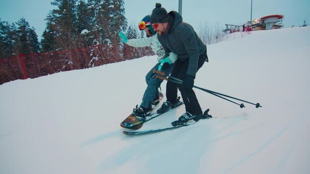 First time on snowboard. Woman learns snowboarding on the slope with her friend