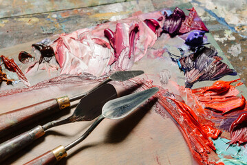Palette knives lie on a palette with dried spots of oil paint.