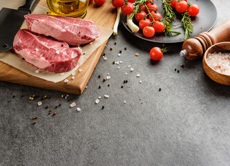 Meat, vegetables and condiments on a dark background with copy space.