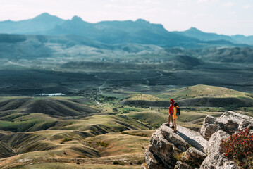 A happy couple in the mountains admires the beautiful views. A man and a woman with backpacks on the mountain admire the panoramic view. Travelers enjoy climbing the mountain. Copy space