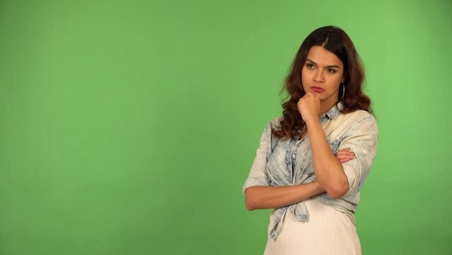 A young beautiful Caucasian woman thinks about something - green screen background