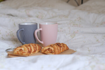 Cozy breakfast in bed. Gray and pink mugs with Maple syrup puffs with pecans on linen. Bakery.