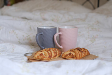Cozy breakfast in bed. Gray and pink mugs with Maple syrup puffs with pecans on linen. Bakery.