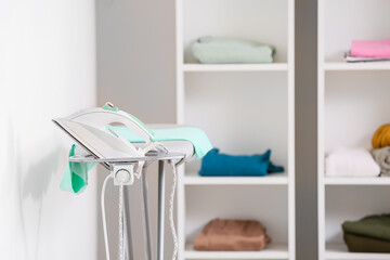 Board with modern electric iron in light laundry room