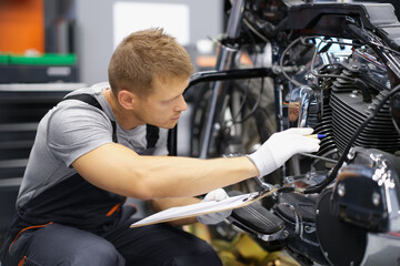 A mechanic sits in a workshop near a motorcycle