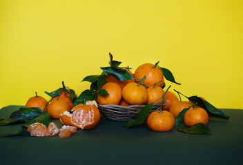 Fragrant citrus fruits on a yellow background. Mandarins with leaves on a colored background. The smell of christmas, alphabet of vitamins. Poster in a cafe or restaurant. Artistic view of fruit